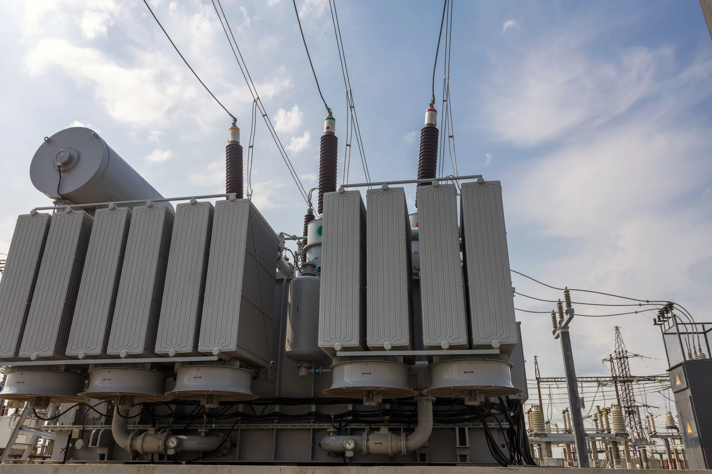 High voltage transformer against a blue sky background. Electric current redistribution substation